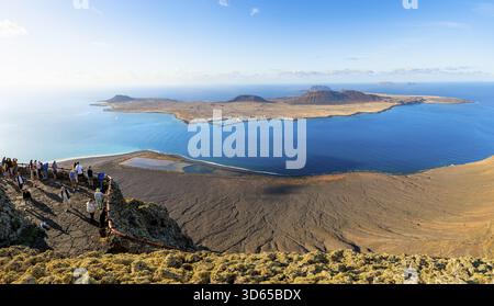 Vue sur l'île de la Graciosa avec des cratères volcaniques dans la lumière du soir, les touristes sur une plate-forme d'observation au point de vue Mirador del Rio conçu par A. Banque D'Images