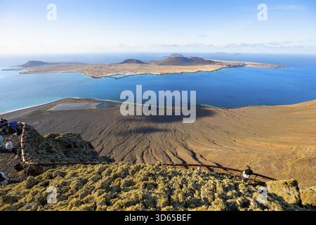 Vue sur l'île de la Graciosa avec des cratères volcaniques dans la lumière du soir, les touristes sur une plate-forme d'observation au point de vue Mirador del Rio conçu par A. Banque D'Images