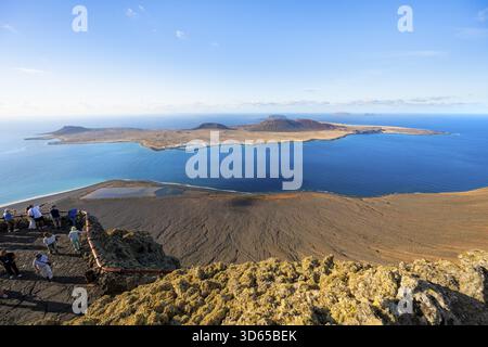 Vue sur l'île de la Graciosa avec des cratères volcaniques dans la lumière du soir, les touristes sur une plate-forme d'observation au point de vue Mirador del Rio conçu par A. Banque D'Images