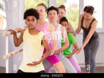 Adolescent afro-américain maîtrisant demi-plie à la barre au cours de ballet Banque D'Images