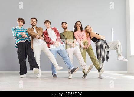 Groupe de danse amical de jeunes gens drôles heureux activement amusants dansant à l'intérieur, se déplaçant ensemble Banque D'Images