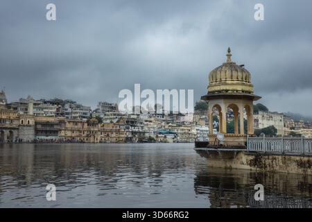 Lac Pichola avec une architecture historique au bord du lac et un pavillon en forme de dôme à Udaipur un jour couvert. Banque D'Images