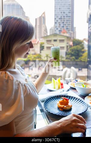 Jeune femme dînant dans un restaurant urbain, profitant d'un vert rafraîchissant Banque D'Images