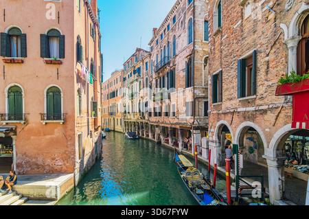 Vue sur un bras latéral du Grand canal, avec des bateaux et des façades colorées de maison, Venise, Italie Banque D'Images