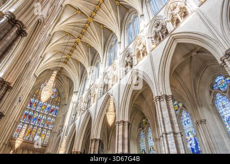 Découvrez l'architecture gothique complexe de l'abbaye de Westminster, avec de superbes arches, des vitraux détaillés et de splendides lustres qui illuminent l'intérieur historique. Banque D'Images