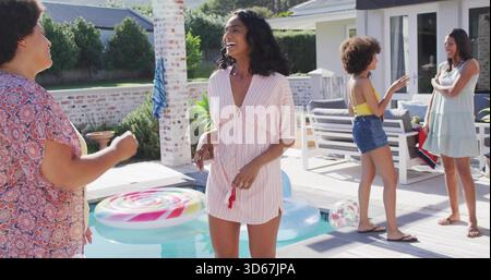 Femme riante portant une robe rayée tenant un objet rouge sur le pont près de la piscine plongeante, avec flotteur de sucette Banque D'Images