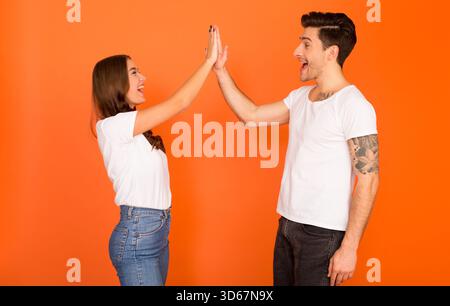 Heureux gars et femme donnant haut cinq, saluant l'un l'autre Banque D'Images