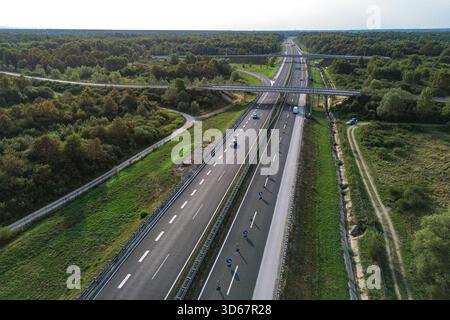Vue aérienne d'une autoroute moderne traverse la dense forêt verte, un contraste frappant entre la nature et les infrastructures, Zagreb, Croatie. Banque D'Images
