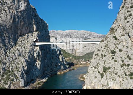 Vue aérienne d'un pont moderne traversant d'imposantes falaises, suspendu au-dessus des eaux chatoyantes de la rivière Cetina, Omiš, comté de Split-Dalmatie, Cro Banque D'Images