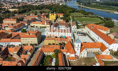 Vue aérienne des toits en terre cuite embrassés par le soleil rencontre le charme baroque de la colonne de la Sainte Trinité dans la vieille ville, encadrée par la rivière Drava, Osijek, OS Banque D'Images