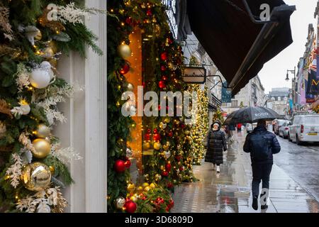 New Bond Street, Londres, Royaume-Uni. 19 novembre 2025. Le froid et le grésil tombant à Mayfair par temps gris avec des boutiques colorées décorées pour Noël 2025. Crédit : Malcolm Park/Alamy Live News Banque D'Images