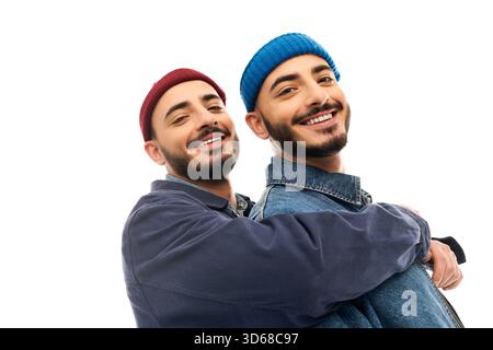Deux frères jumeaux vêtus d'une tenue tendance s'embrassent avec des expressions joyeuses. Banque D'Images