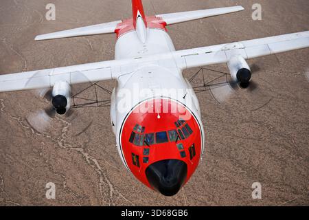 Lockheed C-130A Hercules (N117TG) exploité par International Air Response lors d'une mission de photographie air-air au-dessus de l'Arizona. Ce Hercules de premier modèle, série 182-3018, est capturé en vol au-dessus du paysage désertique, mettant en valeur le profil distinctif et la conception traditionnelle du transport à turbopropulseurs à quatre moteurs classique Banque D'Images