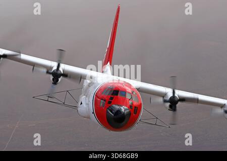 Lockheed C-130A Hercules (N117TG) exploité par International Air Response lors d'une mission de photographie air-air au-dessus de l'Arizona. Ce Hercules de premier modèle, série 182-3018, est capturé en vol au-dessus du paysage désertique, mettant en valeur le profil distinctif et la conception traditionnelle du transport à turbopropulseurs à quatre moteurs classique Banque D'Images