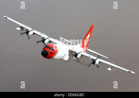 Lockheed C-130A Hercules (N117TG) exploité par International Air Response lors d'une mission de photographie air-air au-dessus de l'Arizona. Ce Hercules de premier modèle, série 182-3018, est capturé en vol au-dessus du paysage désertique, mettant en valeur le profil distinctif et la conception traditionnelle du transport à turbopropulseurs à quatre moteurs classique Banque D'Images