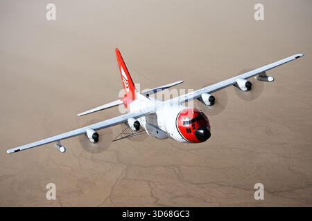 Lockheed C-130A Hercules (N117TG) exploité par International Air Response lors d'une mission de photographie air-air au-dessus de l'Arizona. Ce Hercules de premier modèle, série 182-3018, est capturé en vol au-dessus du paysage désertique, mettant en valeur le profil distinctif et la conception traditionnelle du transport à turbopropulseurs à quatre moteurs classique Banque D'Images