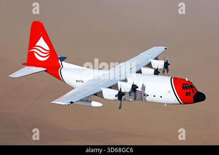 Lockheed C-130A Hercules (N117TG) exploité par International Air Response lors d'une mission de photographie air-air au-dessus de l'Arizona. Ce Hercules de premier modèle, série 182-3018, est capturé en vol au-dessus du paysage désertique, mettant en valeur le profil distinctif et la conception traditionnelle du transport à turbopropulseurs à quatre moteurs classique Banque D'Images