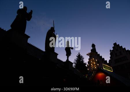 Weihnachtsmarkt auf dem Römerberg in Frankfurt Die Silhouetten der Stadtgrößen Frau Rauscher links, Karl der Große Mitte und Johann Wolfgang Goethe rechts, die sich auf dem Dach einer Weihnachtsmarktbude auf dem Römerberg in Frankfurt am main befinden, zeichnen sich gegen den blauen Abendhimmel ab. Der Frankfurter Weihnachtsmakrt beginnt am 24. November und geht bis zum 22. Dezember. Francfort-sur-le-main Römerberg Hessen Deutschland *** marché de Noël sur la Römerberg à Francfort les silhouettes de la ville grands MRS Rauscher à gauche, Charlemagne au milieu et Johann Wolfgang Goethe Banque D'Images