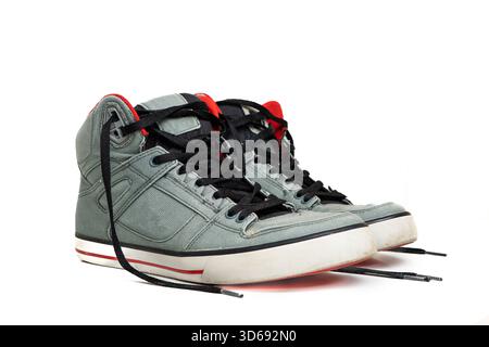 Une paire de baskets montantes en toile grise usagées avec des lacets noirs non noués et des accents rouges. Studio shot, isolé sur blanc, pas de gens Banque D'Images