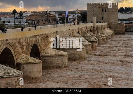 Sud de l'Espagne par temps hivernal humide : après une semaine de fortes pluies, l'eau brune jaillit à travers d'anciennes arches arrondies et pointues du Puente Romano ou pont romain reconstruit du 1er siècle après JC enjambant le fleuve Guadalquivir à Córdoba, Andalousie. La Torre de la Callahorra ou Tour Callahorra du XIIe siècle défend son extrémité sud. Banque D'Images