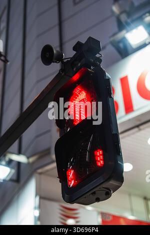Le signal rouge ne pas marcher s'allume au-dessus d'une rue animée de Tokyo la nuit Banque D'Images