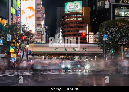 La foule nocturne traverse Shibuya Scramble par le panneau JR Shibuya Station Banque D'Images