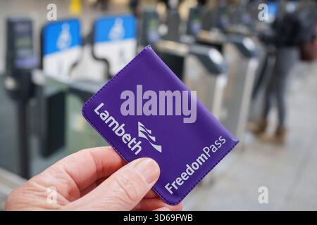 Gros plan détaillé d'une main tenant un Freedom Pass délivré par le Conseil de Lambeth à la gare de Farringdon, le 19 novembre 2025, à Londres, en Angleterre. Les Freedom Pass permettent aux plus de 66 ans de voyager gratuitement en dehors des heures de pointe à travers Londres, ainsi que de voyager en bus en dehors des heures de pointe dans le reste de l'Angleterre. Le régime financé par les conseils londoniens a cependant été critiqué pour ses dépenses de fonctionnement qui, en 2024/5, s'élevaient à 291 millions de livres sterling Banque D'Images