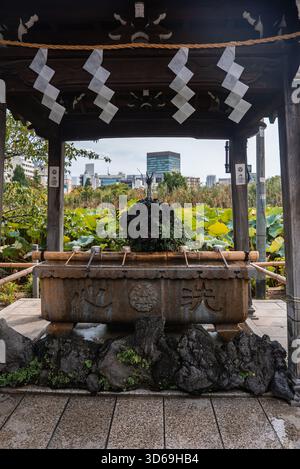 Shinto temizuya au parc Ueno avec étang de lotus et horizon de Tokyo Banque D'Images