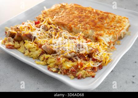 Vue sur une assiette de petit-déjeuner avec bacon, saucisses, œufs brouillés et pommes de terre sautées. Banque D'Images