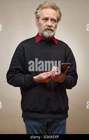 Vieil homme de plus de 60 portrait en studio avec smartphone Banque D'Images