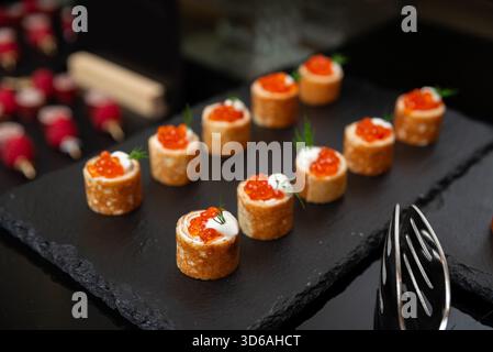 Une sélection de hors-d'œuvre gastronomique magnifiquement arrangée avec œufs de saumon sur un plateau d'ardoise. cette présentation élégante met en valeur une cuisine raffinée Banque D'Images