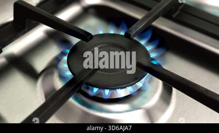 Gros plan d'une cuisinière à gaz brûlante avec des flammes bleues sur une surface en acier inoxydable. Fond de cuisine à la maison. Bannière Banque D'Images
