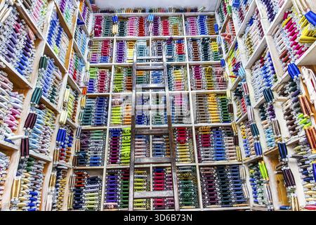 Fes, Maroc â€“ affichage vibrant de rouleaux de tissu coloré soigneusement empilés dans un magasin de textile marocain traditionnel. Les étagères organisées et ladd en bois Banque D'Images