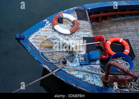 Gros plan du pont de bateau de pêche altéré avec des filets et des bouées de sauvetage Banque D'Images