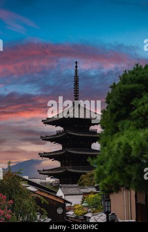 La pagode Yasaka s'élève au-dessus des toits de Kyoto au coucher du soleil avec des collines au-delà Banque D'Images