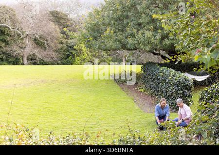 Mère et fille adulte travaillant à la haie dans le jardin plantant des plants sous hamac, espace de copie Banque D'Images