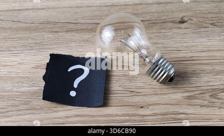 Nouvelle idée question et concept de recherche d'inspiration avec point d'interrogation et ampoule sur fond en bois Banque D'Images