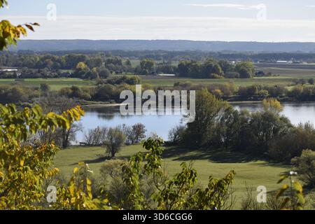 Rivière bleu vert entouré d'arbres denses avec des champs de feuillage d'automne et des collines boisées créent une atmosphère naturelle calme Banque D'Images