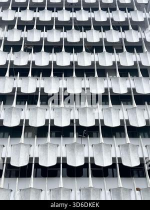 Photographie verticale et à angle bas de l'extérieur d'un immeuble de grande hauteur. La façade est recouverte d'éléments de béton uniformes, en forme de pelle ou en forme de bêche Banque D'Images