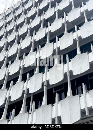 Photographie verticale et à angle bas de l'extérieur d'un immeuble de grande hauteur. La façade est recouverte d'éléments de béton uniformes, en forme de pelle ou en forme de bêche Banque D'Images