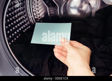 Main de la personne tenant et utilisant la feuille de détergent à lessive, poudre de lavage concentrée pour machine à laver. Travail de nettoyage de blanchisserie à la maison. Banque D'Images