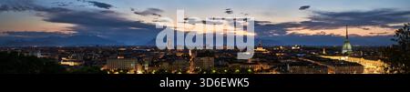 Torino Turin vue panoramique au crépuscule, avec la ligne d'horizon de la ville avec l'emblématique mole Antonelliana, bâtiments illuminés. Les Alpes lointaines se silhouettent Banque D'Images