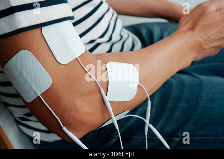 vue rapprochée d'un homme assis avec des électrodes connectées à un dispositif d'électrothérapie pour le traitement de récupération musculaire Banque D'Images