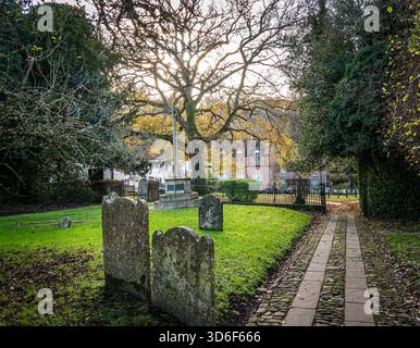 Vue de l'église St Mary, Selborne, Hampshire, montrant le cimetière et les chalets en face. Banque D'Images