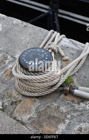Lourdes cordes attachées autour de la borne d'amarrage de bateau en métal pour ancrer à la photo verticale du quai Banque D'Images