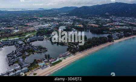 Plage tropicale baignée de soleil et eau turquoise limpide de l'océan parallèle à un grand complexe de luxe construit autour de lagons artificiels sombres Banque D'Images