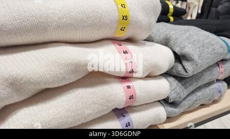 Pile de chandails soigneusement pliés étiquetés avec différentes tailles pour la présentation de vêtements au détail Banque D'Images