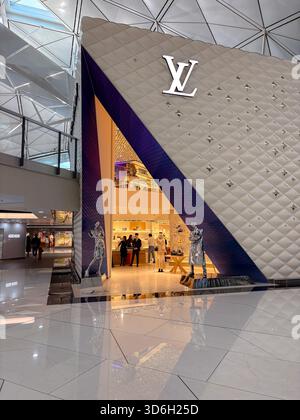Le magasin Louis Vuitton, avec sa façade moderne matelassée et son logo proéminent à l'intérieur du terminal animé de l'aéroport international de Hong Kong, met en valeur le luxe Banque D'Images