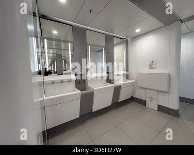 Toilettes publiques modernes de l'aéroport international de Hong Kong avec plusieurs lavabos contemporains avec miroirs, éclairage intégré et changeur de bébé Banque D'Images