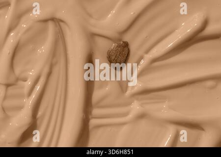 Fond texturé cosmétique abstrait, goutte de vernis à ongles sur la texture de fond de teint liquide beige. Produit mousse de soin crémeux pour la peau en gros plan. Beaut hydratant Banque D'Images